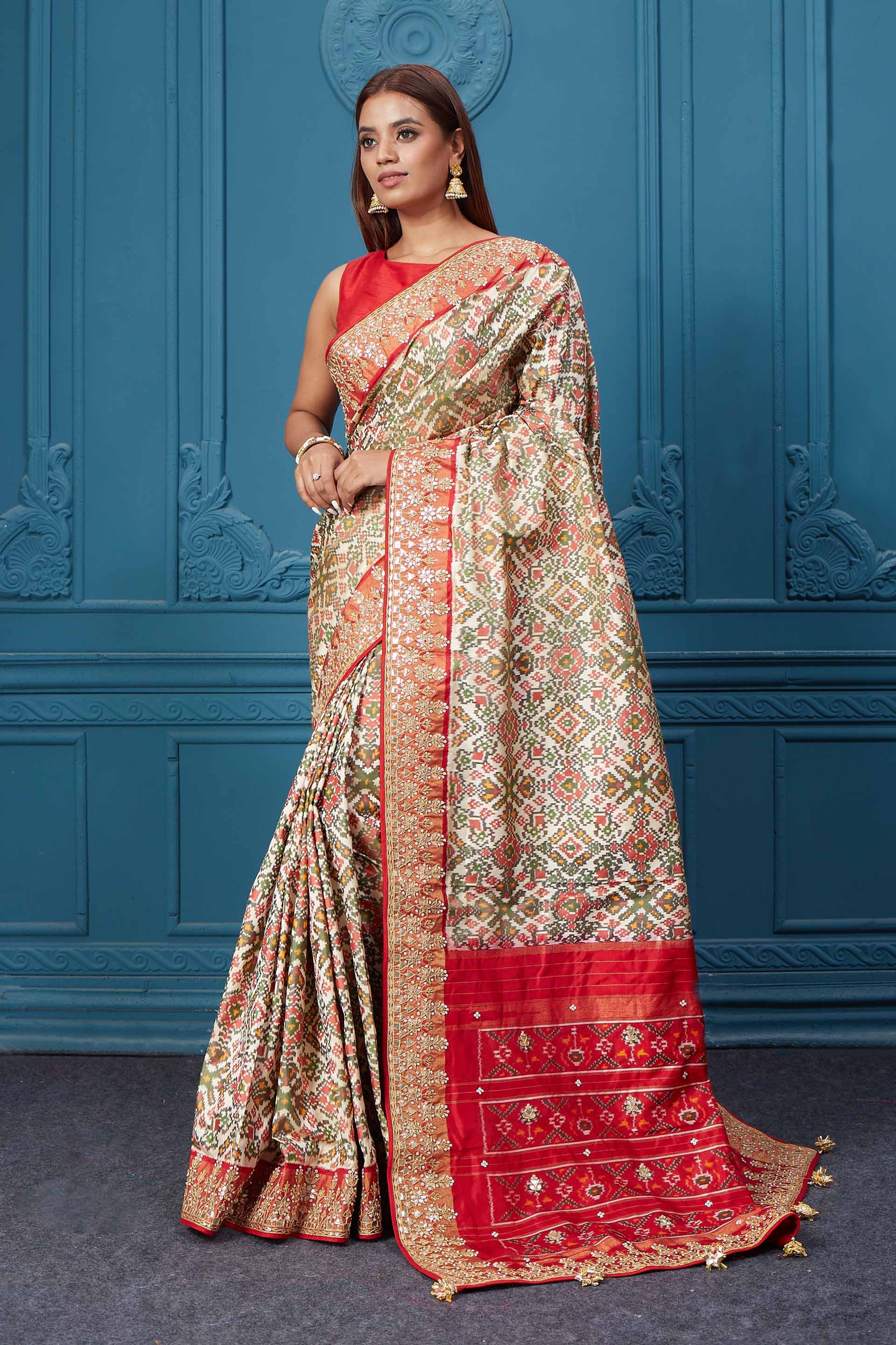 Buy off-white Patola silk saree online in USA with red embroidered border and saree blouse. Look royal at weddings and festive occasions in exquisite designer sarees, handwoven sarees, pure silk saris, Banarasi sarees, Kanchipuram silk sarees from Pure Elegance Indian saree store in USA. -pallu