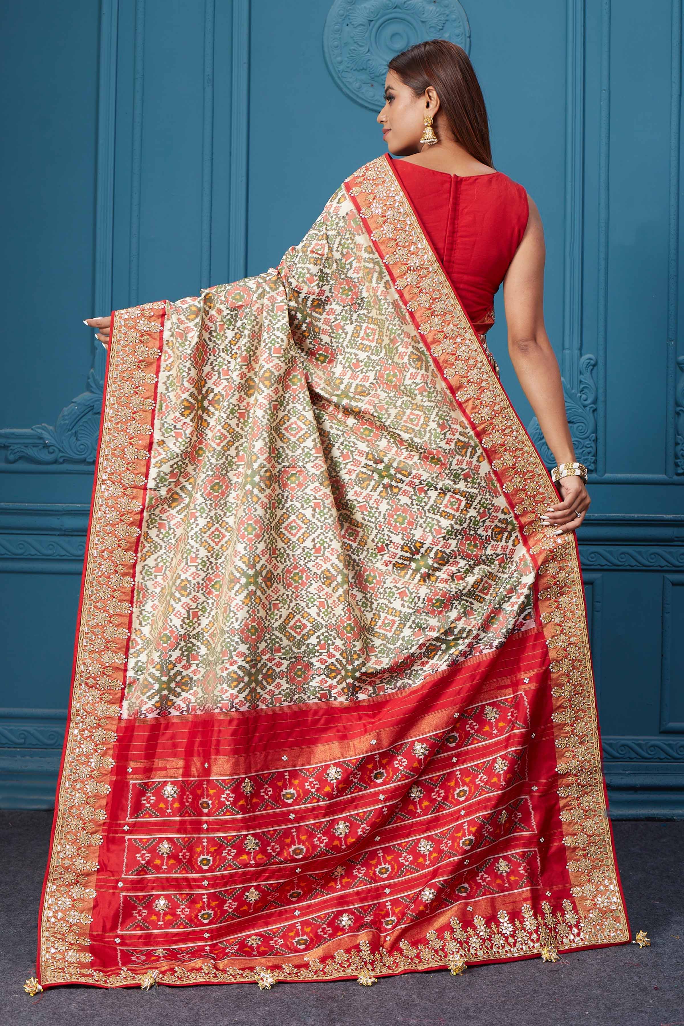Buy off-white Patola silk saree online in USA with red embroidered border and saree blouse. Look royal at weddings and festive occasions in exquisite designer sarees, handwoven sarees, pure silk saris, Banarasi sarees, Kanchipuram silk sarees from Pure Elegance Indian saree store in USA. -back