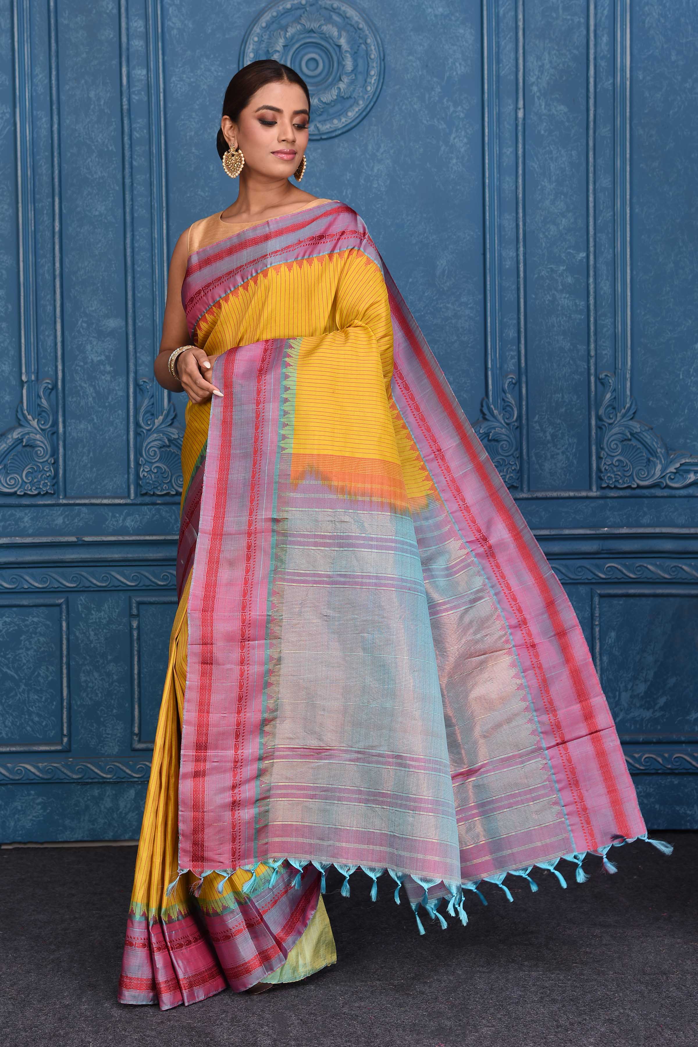 Buy yellow striped pure Gadhwal silk silk sari online in USA with bluish pink border. Keep your ethnic wardrobe up to date with latest designer saris, pure silk sarees, Kanchipuram silk sarees, handwoven silk sarees, tussar silk sarees, embroidered sarees from Pure Elegance Indian saree store in USA.-pallu