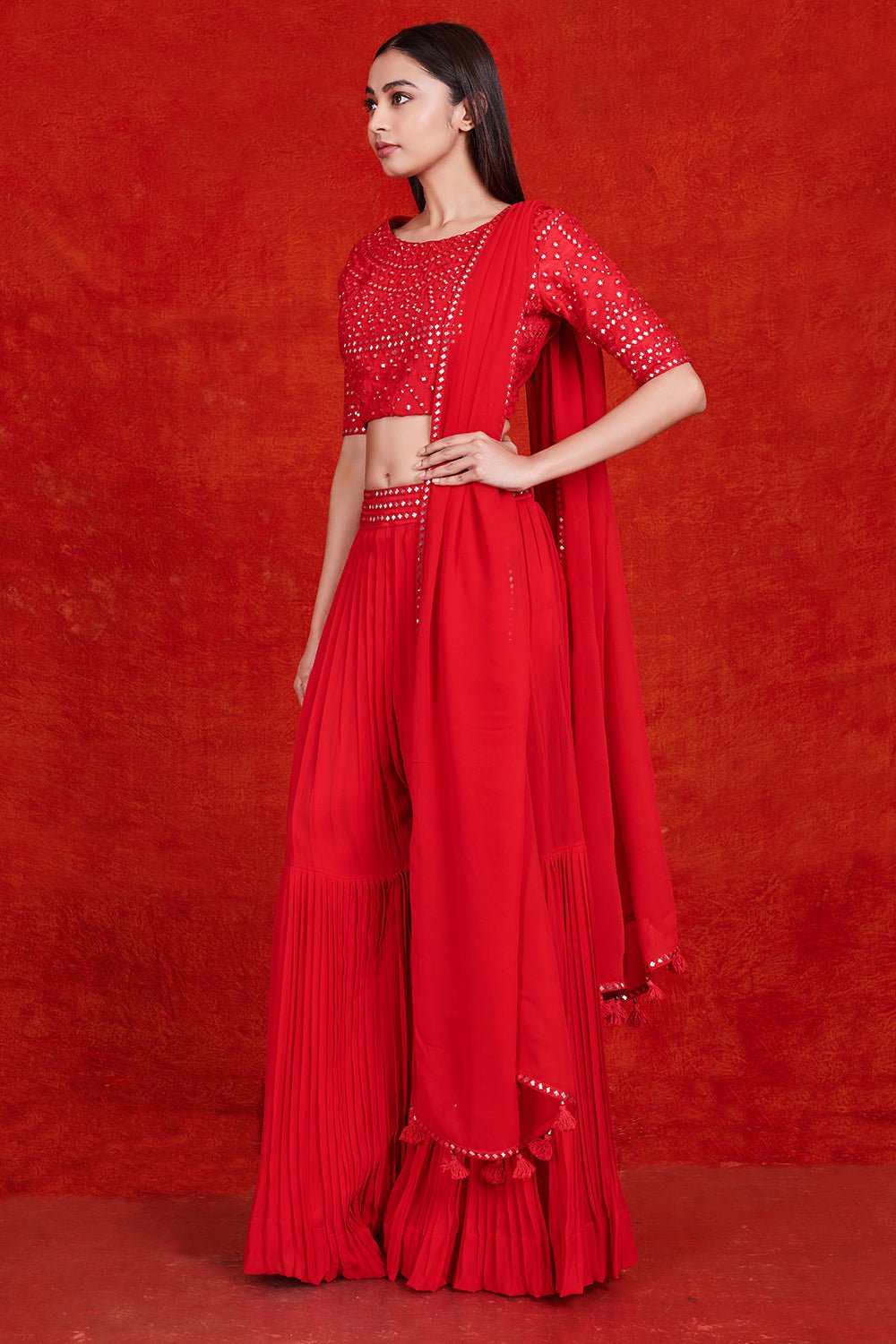 Buy stunning red mirror work sharara suit online in USA with dupatta.  Make a fashion statement on festive occasions and weddings with designer suits, Indian dresses, Anarkali suits, palazzo suits, designer gowns, sharara suits from Pure Elegance Indian fashion store in USA.-left