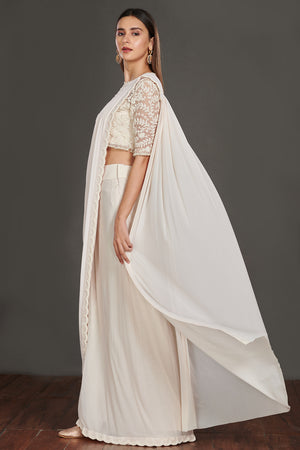 Shop stunning off-white satin saree online in USA with strappy blouse with crop jacket. Make a fashion statement on festive occasions and weddings with designer suits, Indian dresses, Anarkali suits, palazzo suits, designer gowns, sharara suits from Pure Elegance Indian fashion store in USA.-left