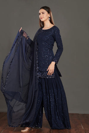 Buy stunning navy blue shimmer sharara suit online in USA. Make a fashion statement on festive occasions and weddings with palazzo suits, sharara suits, partywear dresses, salwar suits from Pure Elegance Indian fashion store in USA.-side look
