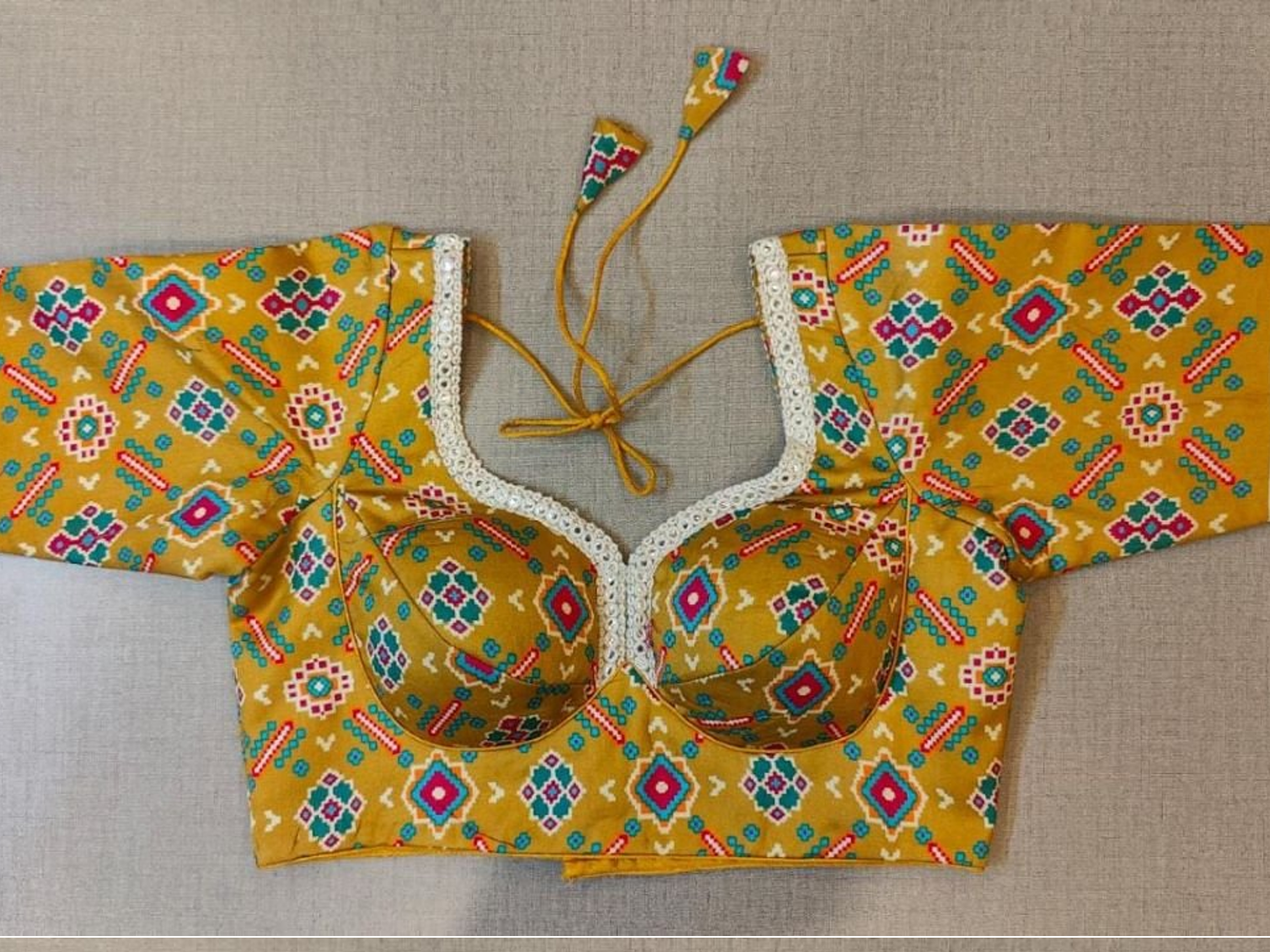 Buy women's yellow Ajrakh Block Printed, padded Saree Blouse that has a round neck, Hook & tie-up closure at back with 3/4th sleeves. Classic is never old and enough to have in your closet!! Pair this fashionable blouse with a beautifully printed sari and statement neckpiece and you are good to go! Buy this designer blouse in the USA from Pure Elegance.- Front View